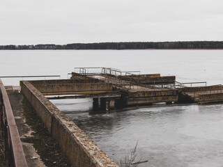 Somber monochromatic landscape with a desolate half-ruined pier. Sense of melancholy and loneliness