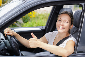 Fototapeta na wymiar young female driver behind the wheel making thumbs up gesture
