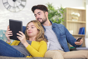 young couple with tablet on sofa indoor