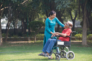 Female physical therapist discussing with senior man in wheelchair at park
