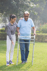 Senior citizen man use a walker in the park with granddaughter.
