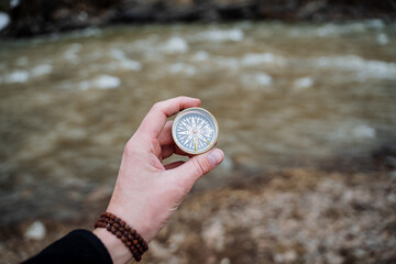 Orienteering in an open area with a compass, the hand holds the compass arrow points north. Survival in the woods, bushcraft.