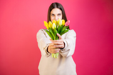 Happy young woman enjoy bouquet of tulips on pink background.