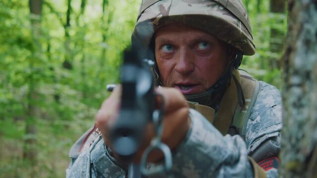 Portrait man soldiers holding machine gun forward to attack enemy in forest. Machine gun barrel look at camera.