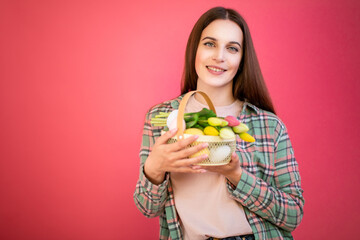 Happy young woman enjoy easter eggs and bouquet of tulips on pink background.
