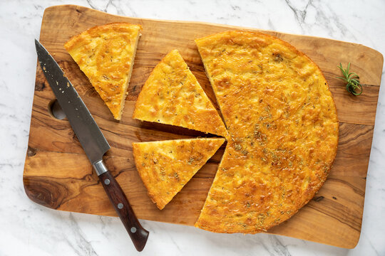 Chickpea pancake Farinata with rosemary herb. Homemade traditional Italian cuisine dish cut in pieces.