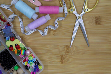 Set of sewing accessories on a wooden background. Fabric, threads, centimeter and scissors.