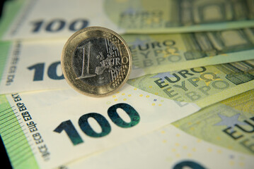 European Union one euro coin and one hundred euro banknotes on a black background macro photo
