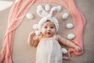 newborn baby lies on a bed in pastel colors like an easter bunny on the grass with eggs
