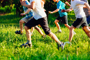 Fototapeta premium Close up of kids legs run down on the grass field.