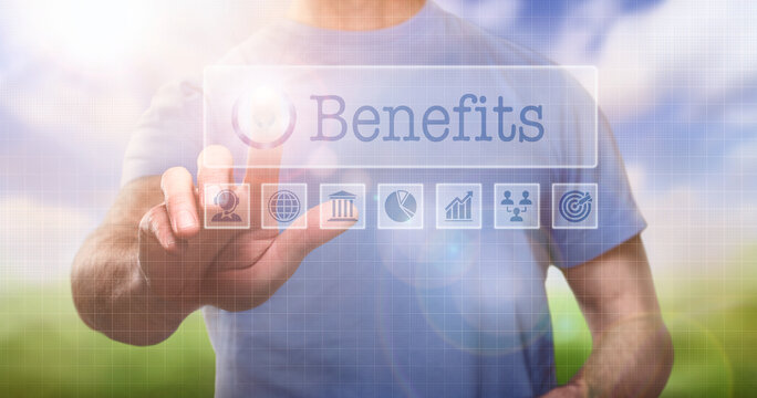 A man in a t-shirt outside selecting a Benefits word concept on a computerised display