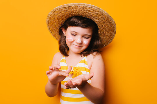 Girl applying suntan cream of face