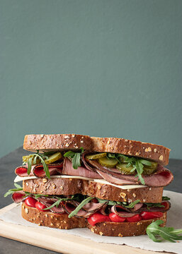 Pastrami sandwich made with wholegrain bread on wooden board