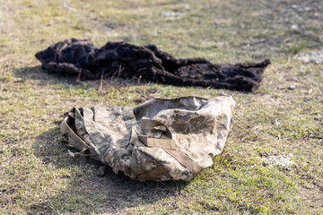 Burned and torn piece of Ukrainian army soldier's pixel camouflage military backpack, he died in the village during battle in a tank. War of Russia against Ukraine. Concept of invasion and genocide. 