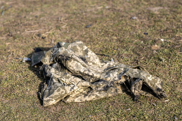 Burned and torn piece of Ukrainian army soldier's pixel camouflage military uniform who died in the village during battle in tank. War of Russia against Ukraine. Concept of invasion and genocide. 