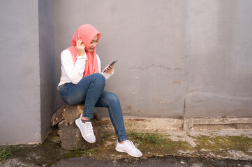 Fototapeta na wymiar Muslim girl listening music from smart phone