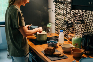 A young blond woman smiles as she cooks food in a home kitchen.