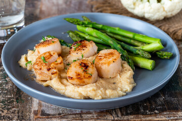 Pan-fried scallops with cauliflower and bean puree and asparagus