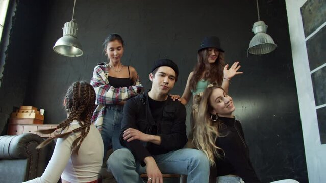 The guy is sitting on a chair while the young pretty girls are dancing around him