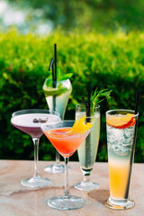 Different cocktails in the restaurant on the background of green leaves.