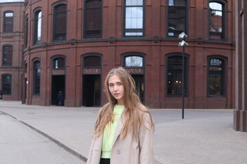 Pretty girl with long hair is taking part in street photo session