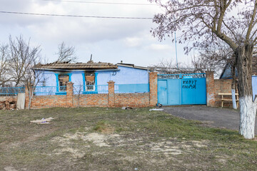 Fototapeta na wymiar Barmashovo, Ukraine- March 18, 2022: War of Russia against Ukraine. Concept of Russian invasion. Burned and devastated house in the center of the village. The words 