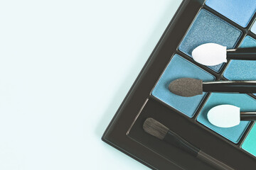 Pallet shadows with appliquators for female eye makeup on blue background. Female makeup and beauty eye. Toned.