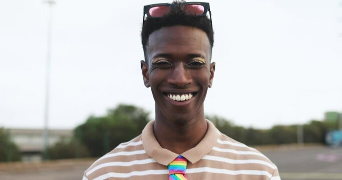 Happy gay african man with make-up smiling on camera outdoor