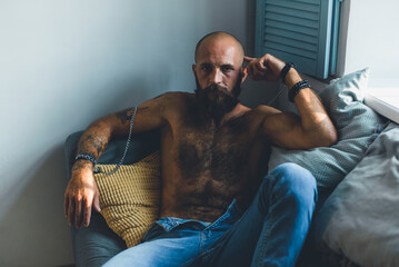 Portrait of a brutal bearded man with a naked torso.