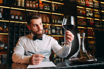 Young handsome man sommelier tasting red wine in cellar.