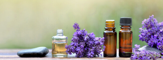 bottles of essential oil and  lavender flowers arranged on a wooden table on blur background