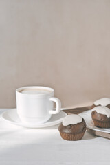 cup of latte coffee and fresh baked cupcakes with icing. chocolate muffins home baked in the morning. vertical shot.