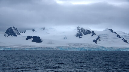 Glacier meeting the Southern Ocean at the base of rugged mountains in Antarctica