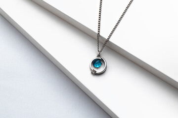 Silver chain necklace with blue diamond pendant on white background