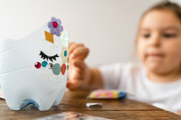 Caucasian preschool girl doing crafts with plastic bottle and paints. Recycle upcycling waste. Sustainable lifestyle