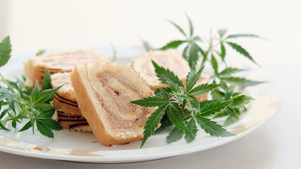 Sweet roll with marijuana oil on white plate. Cannabis kitchen. Layout of delicious dessert, top view close up.