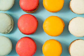 Pastel blue table top with colorful makarons pattern. The concept of minimal sweet food. Cookie concept