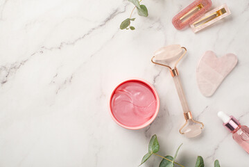 Skincare concept. Top view photo of two barrettes rose quartz roller gua sha pink eye patches...