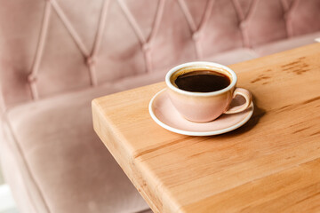 A pink mug of Americano coffee on a wooden table. Aromatic black coffee for breakfast. Stylish creative coffee concept with space for text