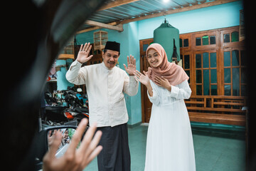 Obraz na płótnie Canvas muslim happy family welcoming guest to their house during eid mubarak idul fitri celebration