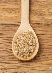 Sesame seeds in a spoon over wooden table