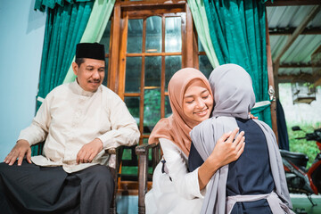 muslim daughter kneel and shake their parent's hand asking for forgiveness on idul fitri celebration at home