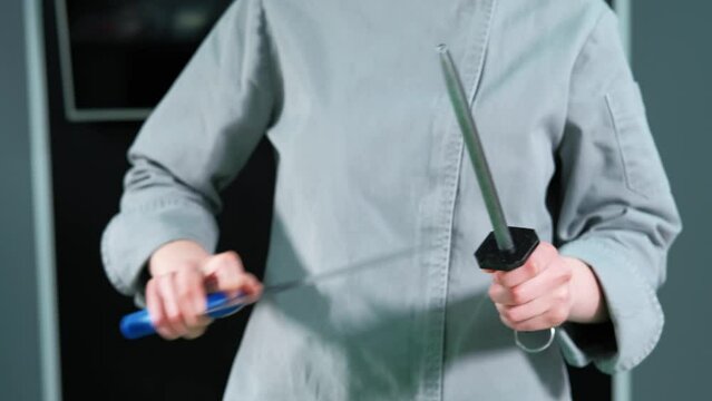 Close up footage of woman chef sharpening knife in kitchen.