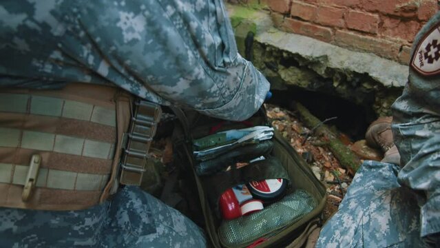 Close-up of combat medic provides first aid. Soldier lying wounded with punctured lungs. Military concept