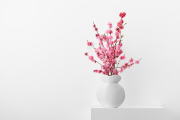 Flowering peach branches in a white vase