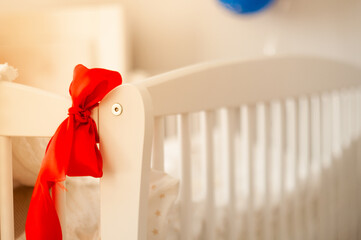 baby cradle close up, with blurred background and red bow