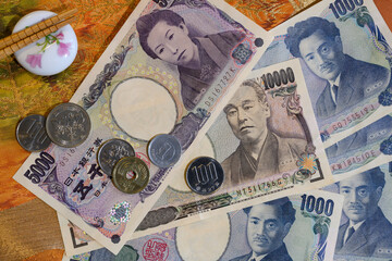 Coins, paper banknotes of Japanese yen and chopsticks on the background of national fabric with...