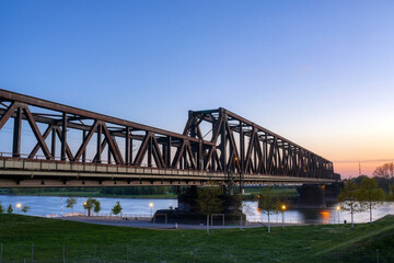 Rheinpark und historische Eisenbahnbrücke in Duisburg Hochfeld bei Sonnenuntergang - obrazy, fototapety, plakaty