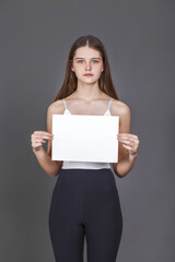 Naklejka premium young girl with a blank sheet of paper - place for an inscription