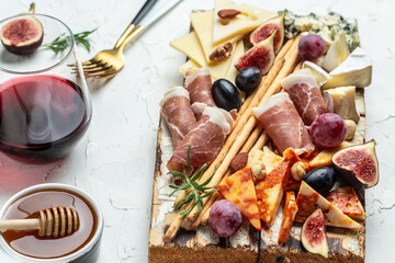 Appetizers table with italian antipasti snacks and wine in glasses. cheese, ham, nuts, fruit, bread sticks. Delicious balanced food concept